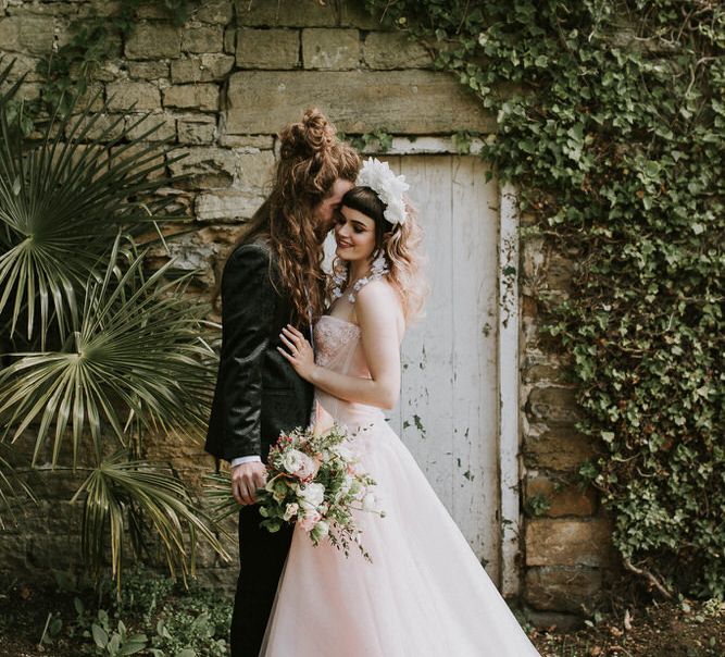 Spring wedding at Hooton Pagnell with bride in a pink strapless wedding dress and groom in a tuxedo embracing 