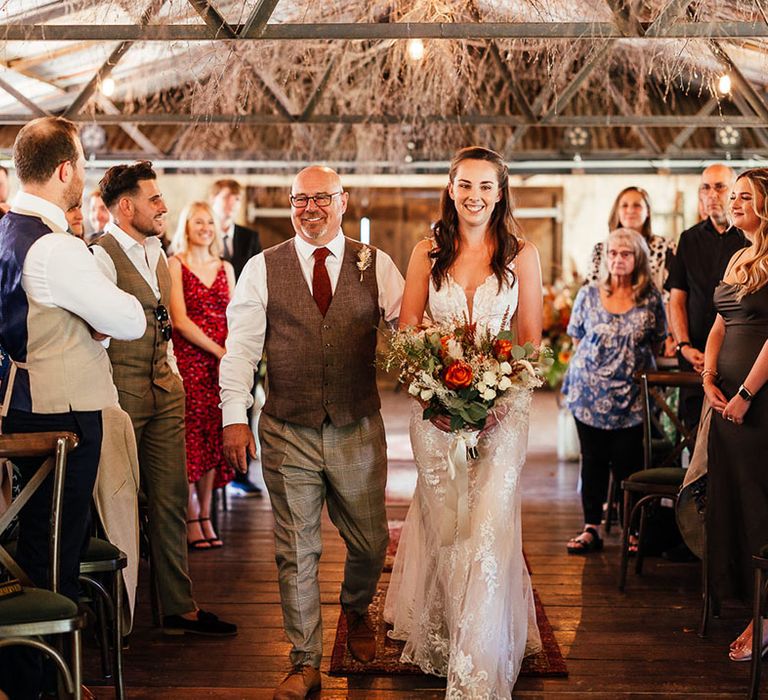 Father of the bride in brown waistcoat walks the bride in a boho lace wedding dress down the aisle at The Dreys wedding venue 