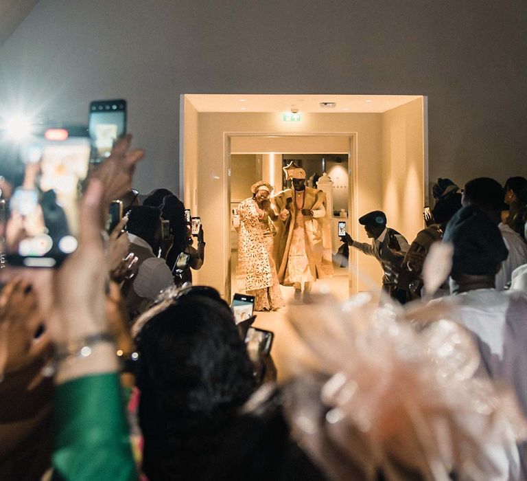 Bride & groom enter reception party as wedding guests take videos and pictures