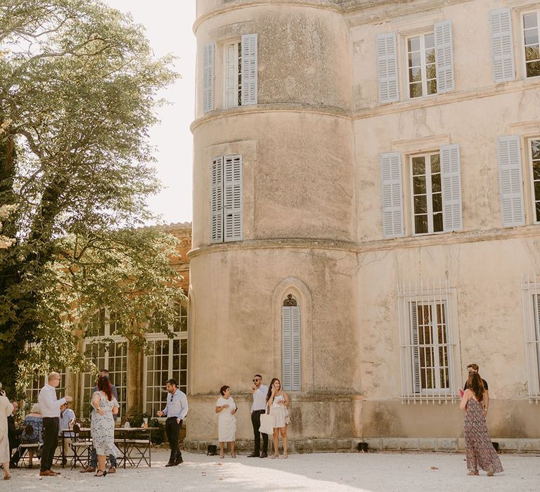 Wedding guests gather outside the Chateau de Robernier before wedding reception outdoors