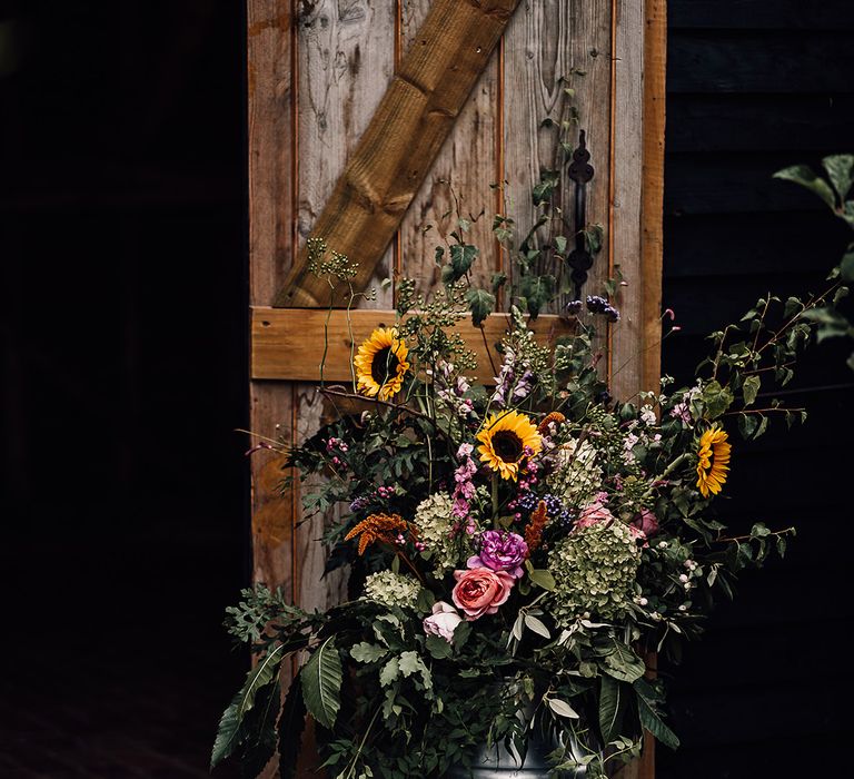 Colourful wedding flowers in a vintage milk churn for rustic barn wedding 