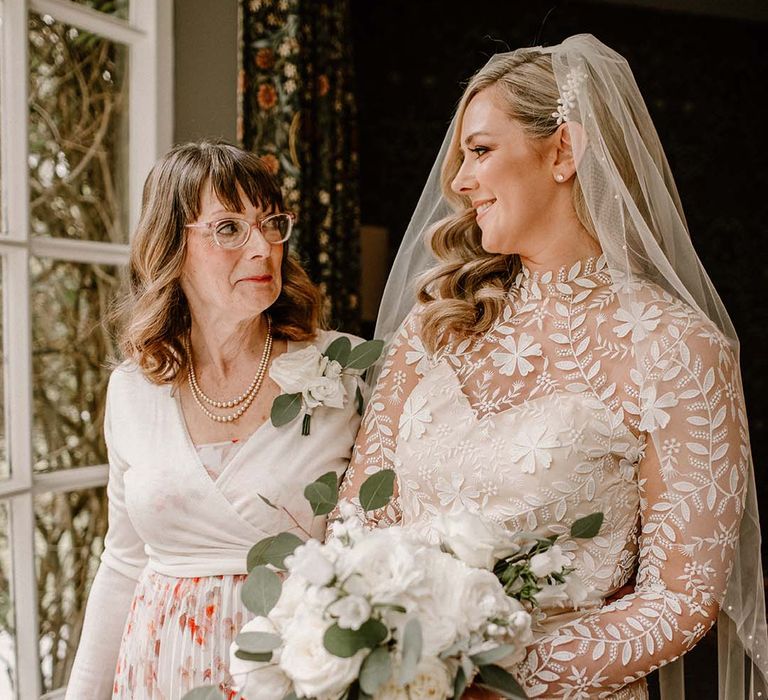 Bride wears high neck wedding dress and cathedral veil with pearl embellishments 