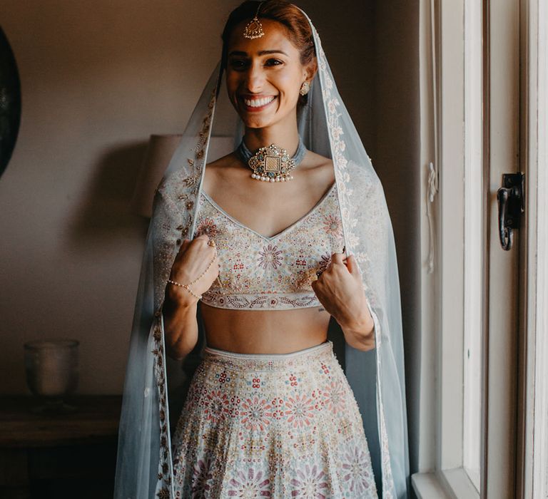 Bride wears colourful lehenga complete with embellished headpiece and statement necklace 