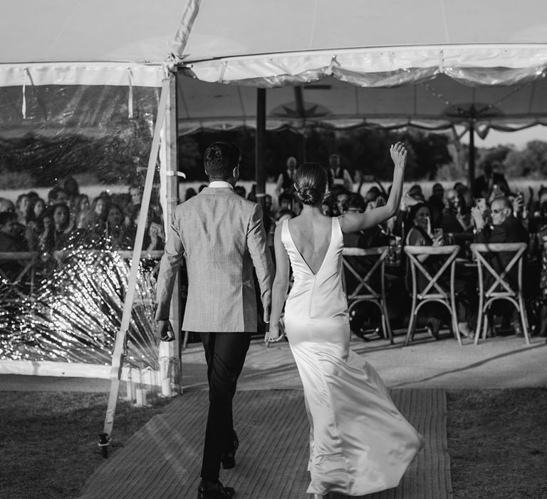 Bride & groom enter black-tie wedding reception in black & white image