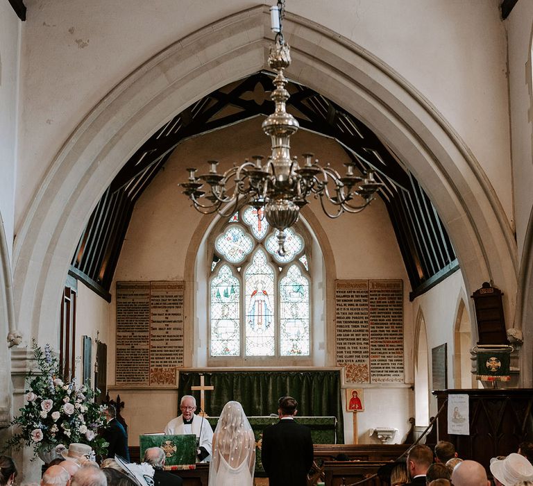 Bride wearing a flower applique veil standing at the altar with the groom for their church ceremony 