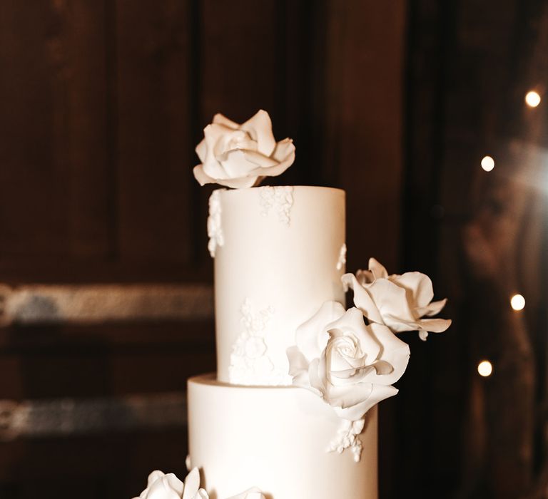 Three tier classic white wedding cake with white rose design 