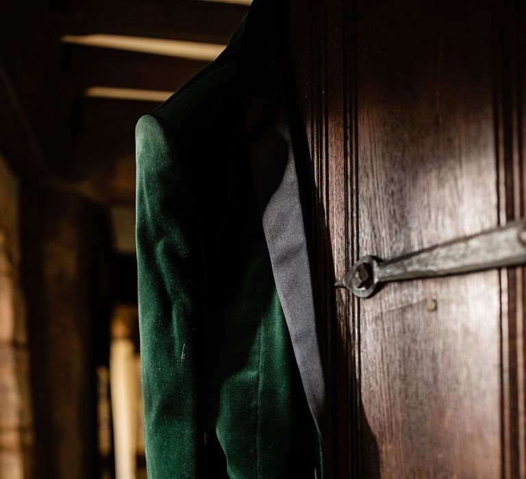 Groom's green velvet tuxedo jacket hanging on the wardrobe door ready for the groom 