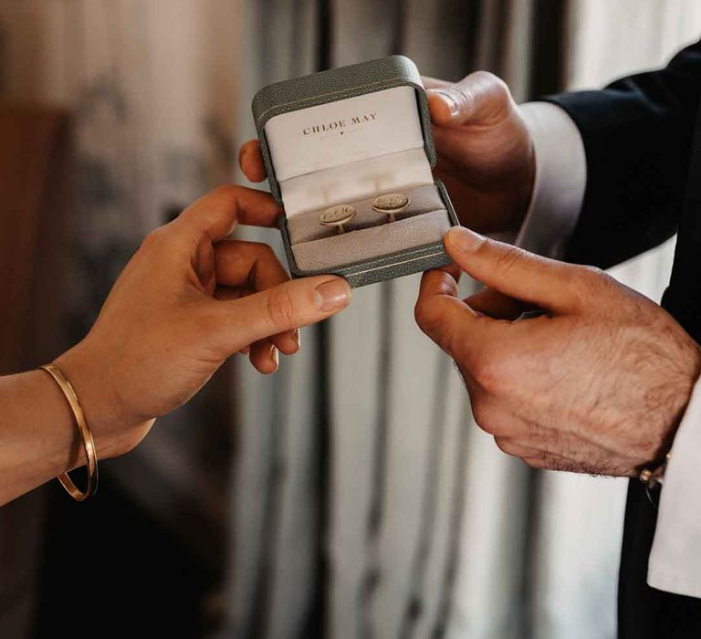 Bride and groom holding grey cufflinks box with personalised cufflinks inside 