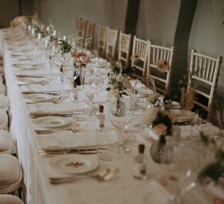 Romantic pink and white wedding tablescape with bud vases and mini bottles of gin for the wedding favours 