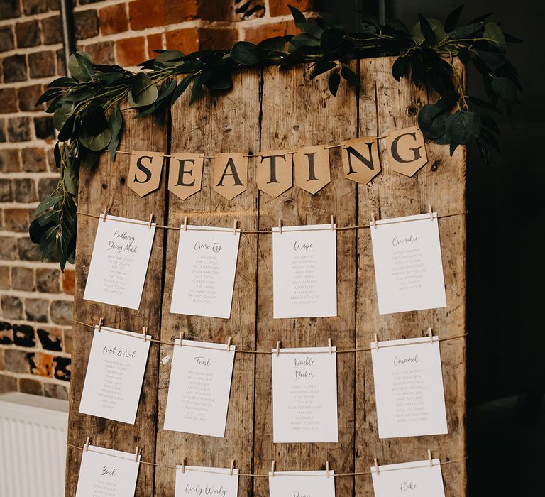 Wooden rustic wedding seating chart with foliage decoration 