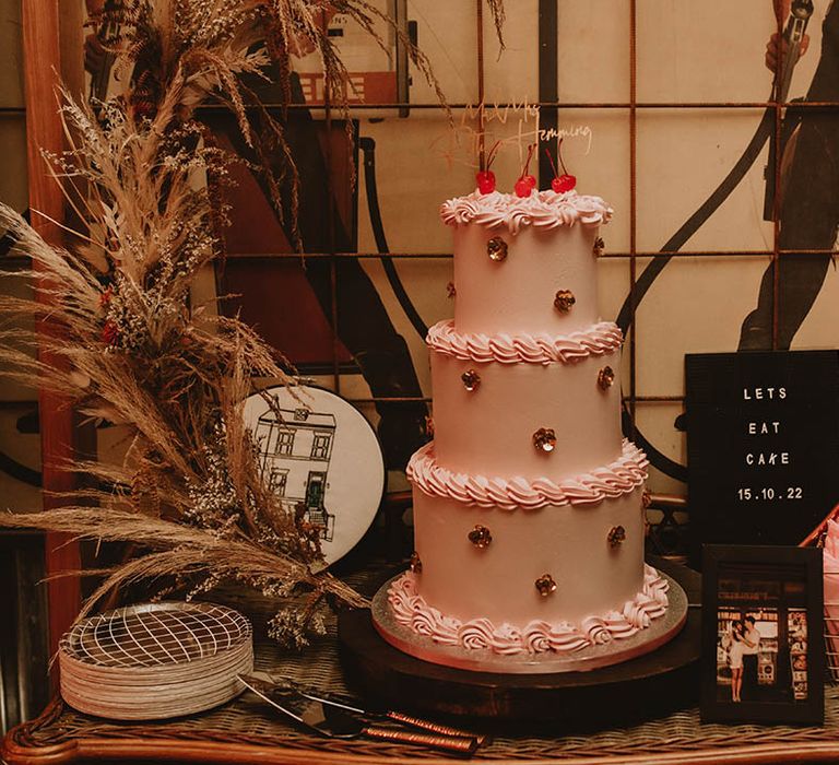 Retro pink wedding with three tiers decorated with flower and maraschino cherries 