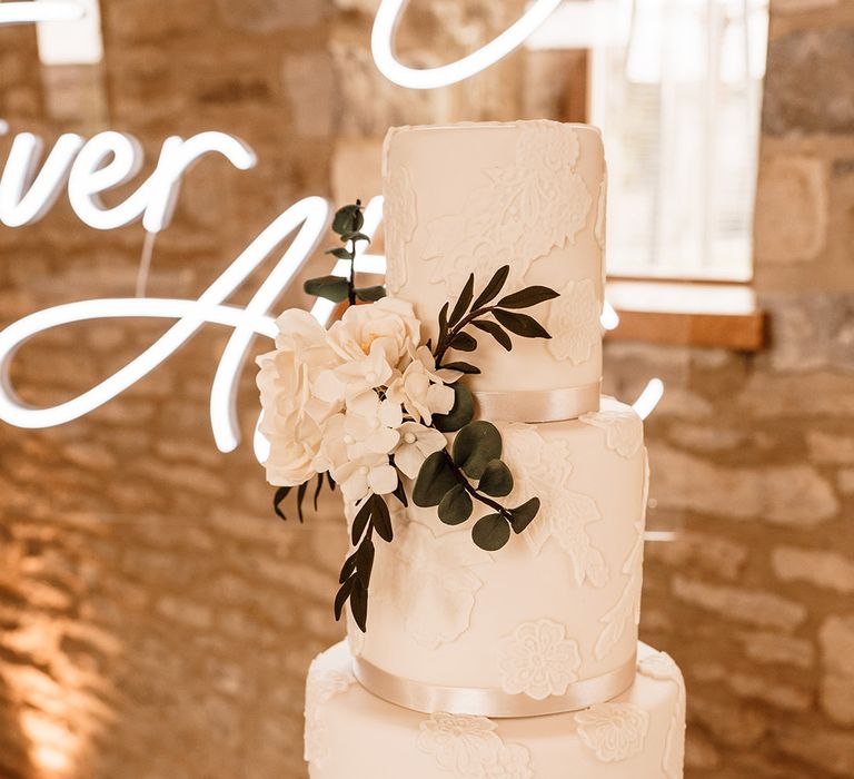 three-tier white iced wedding cake with bow and brooch cake decoration