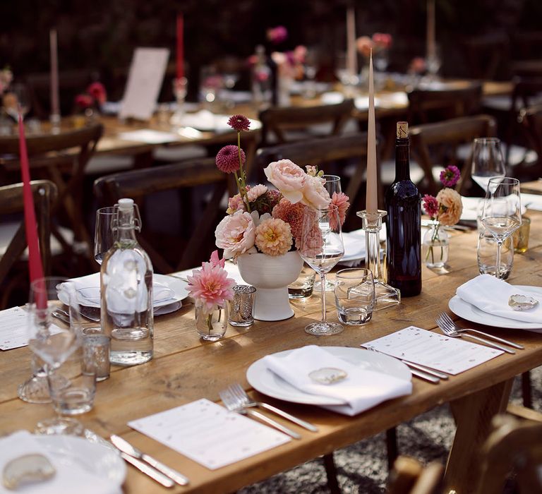 Pink wedding table decorations with pink taper candles and pink flower arrangements with glassware 