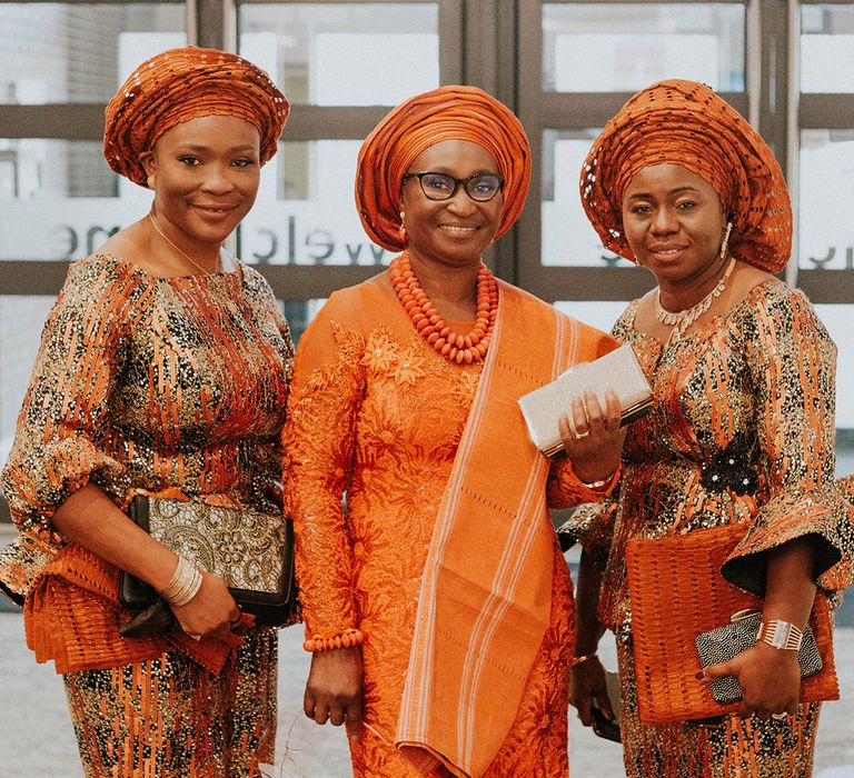 Traditional African wedding outfits with orange wedding headdresses, jewellery and wedding guest outfits 