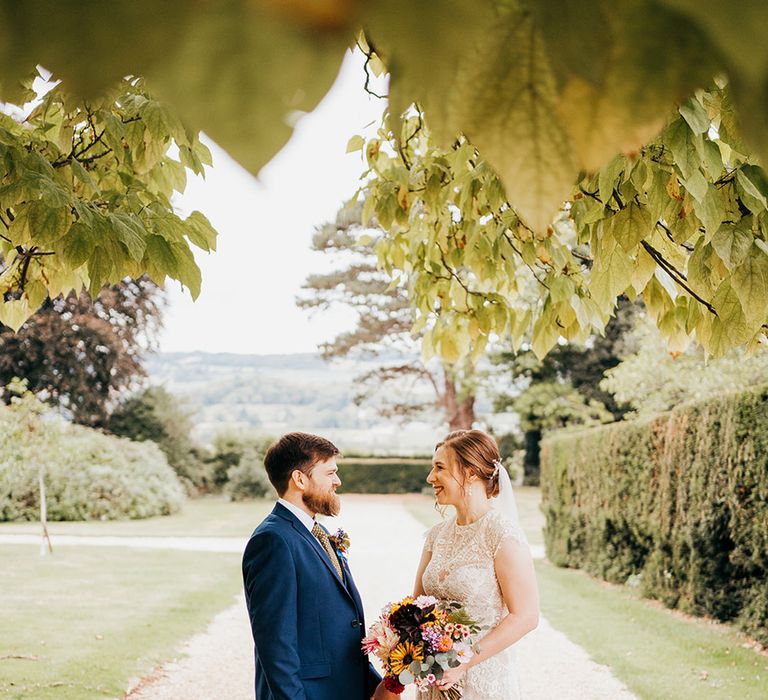 Groom in blue suit with the bride in a delicate lace boho wedding dress posing together 