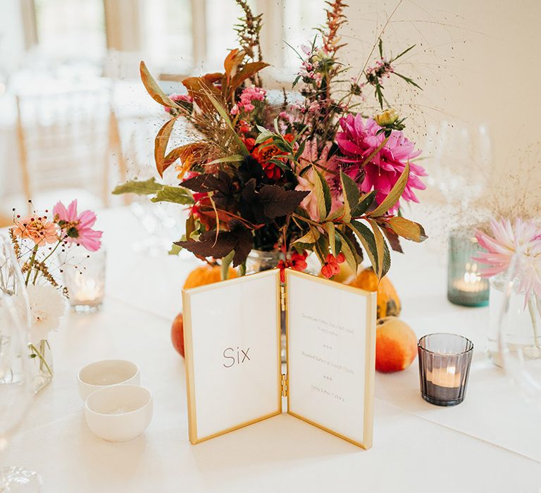 Gold framed wedding table number sign with autumnal table centrepiece on white tablescape 