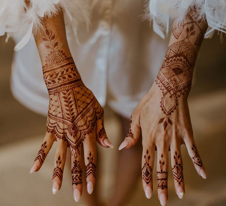 Bride shows off henna wedding design with neutral almond shaped wedding nails 