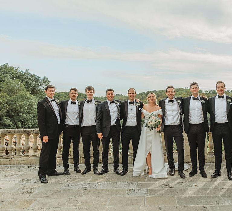 Groomsmen in black tuxedos with the bride in an off the shoulder wedding dress 