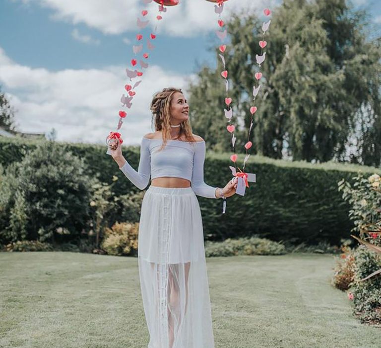 Woman holding pink balloons during boho festival theme hen party by Bai and Elle Photography