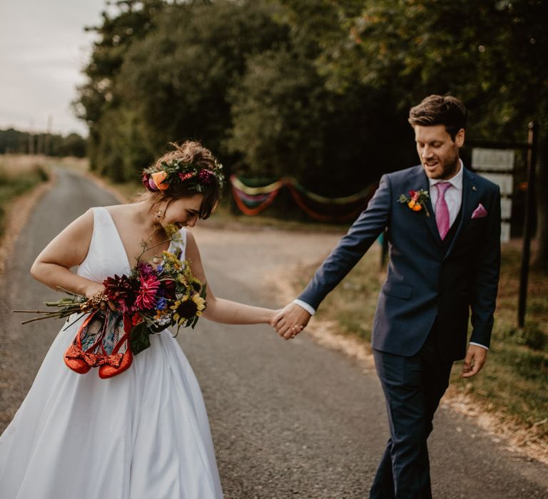 Bride and groom holding hands at Thurstons Farm rainbow wedding