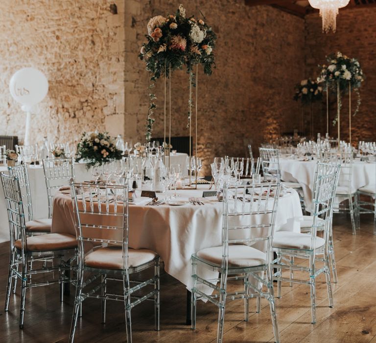 Notley Abbey wedding reception decor with tall floral centrepieces, chandeliers and ghost chairs 