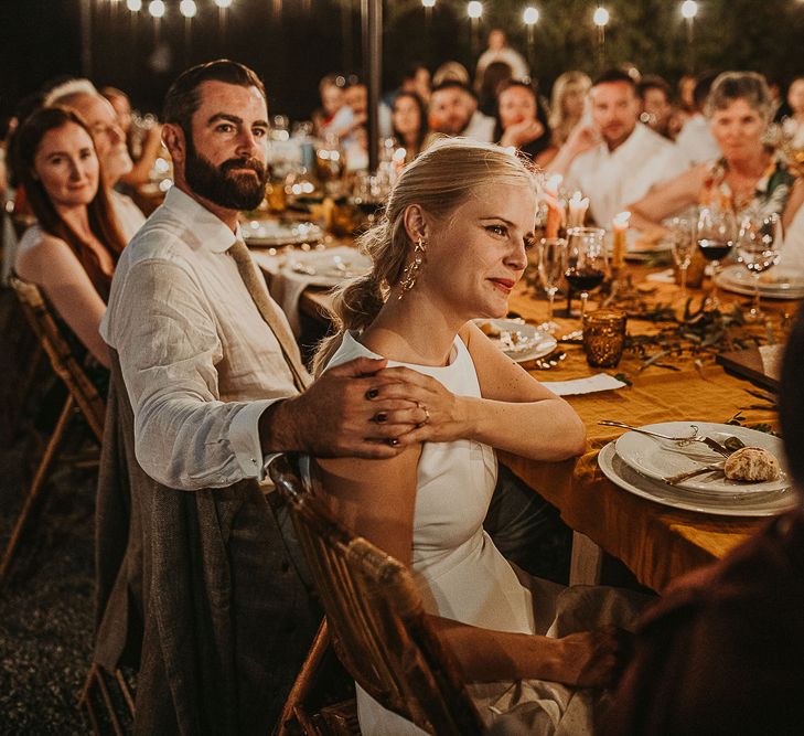 Bride and groom holding hands during outdoor wedding reception 