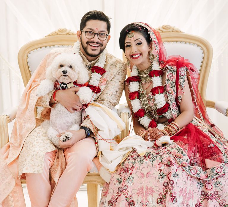 Bride and groom in pink wedding attire with their pet dog