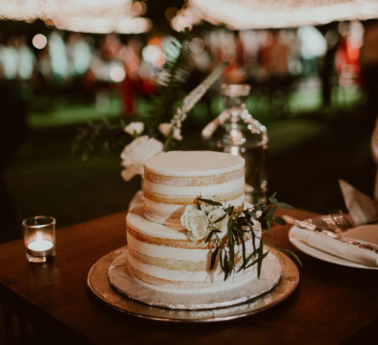 Two tier white naked wedding cake in front of the outdoor dance floor