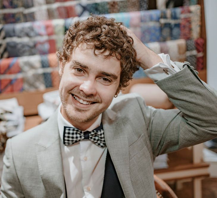 The groom poses in front of a selection of gorgeous wedding ties