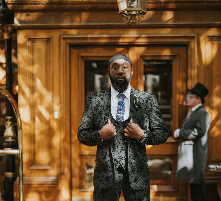 Stylish groom in a three-piece black jacquard suit with horseshoe waistcoat 