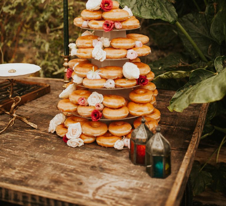 Doughnut tower wedding cake decorated with red flowers, moroccan lanterns and green taper candles 