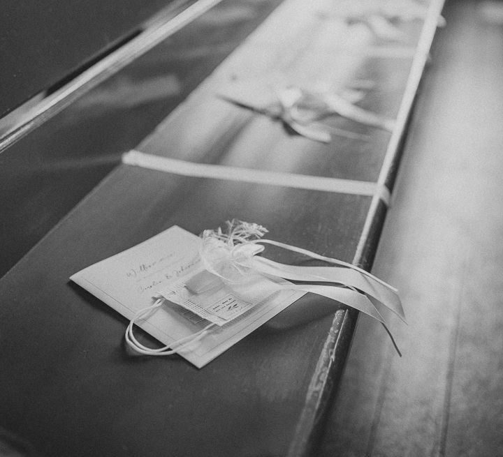 Order of service and face mask favours on wooden pew for German wedding ceremony in church