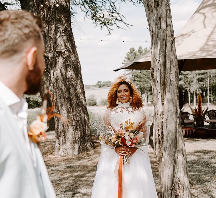 Bride walks toward groom holding brightly coloured dried floral bouquet