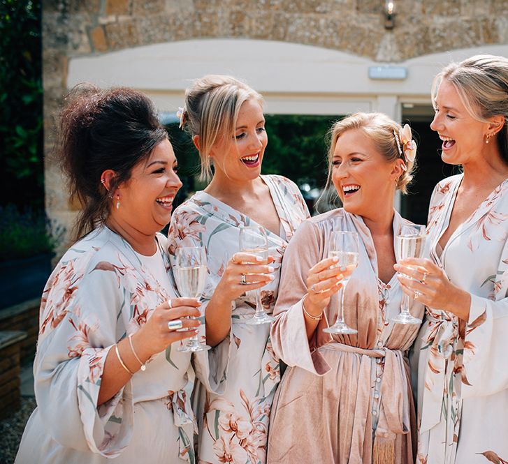 Bridal party raising a toast with champagne on the wedding morning wearing robes outside country barn 