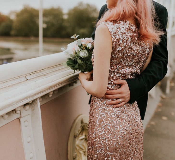 Groom with his arm arounds his brides waist in a sparkly wedding dress