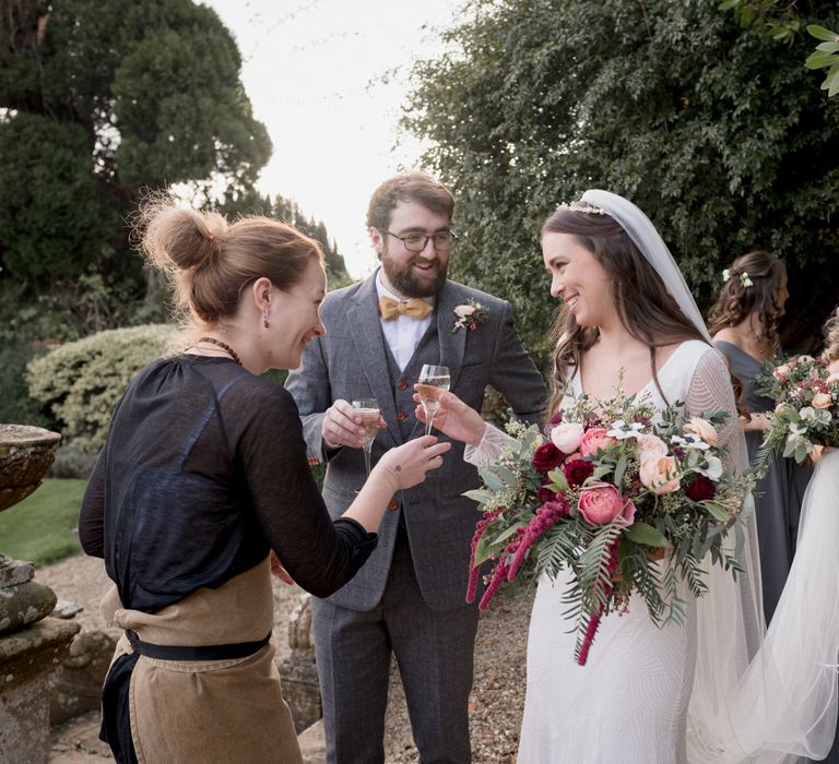 Newly married couple holding champagne glasses outside on their wedding day