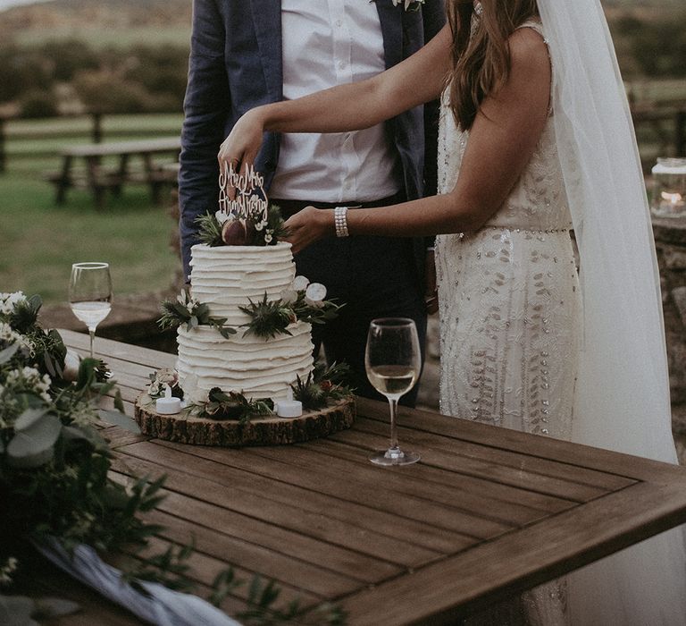 Bride & groom cut cake outdoors on the day of their wedding