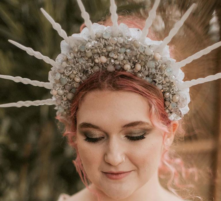 Bride with pink curled hair and beaded crown headband wears gold sequin wedding dress and face gems for festival themed wedding