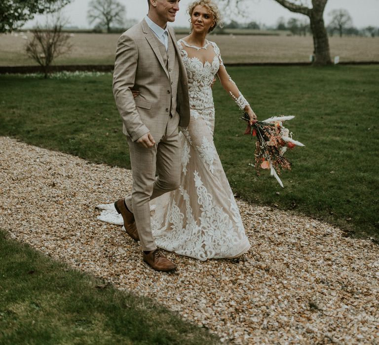 Bride and groom walking arm in arm through Hornington Manor