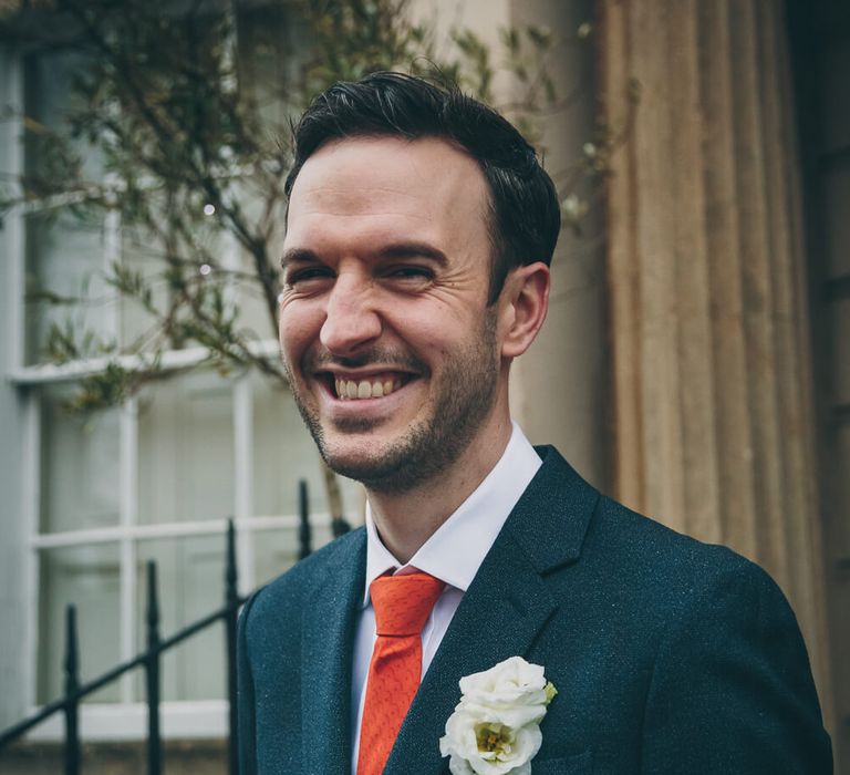 Groom smiling wearing red tie