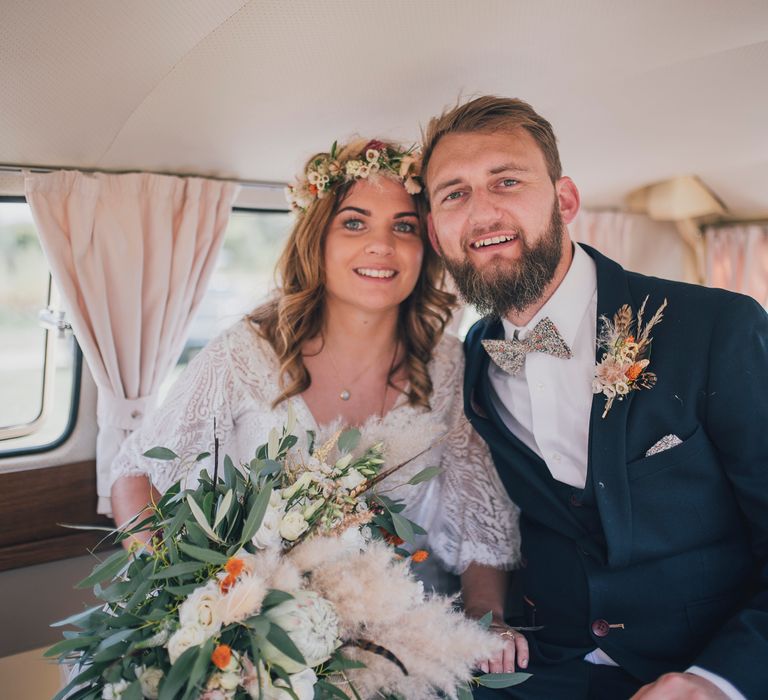 Bride & groom sit and smile together in VW camper van after wedding ceremony