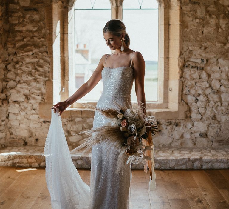 Bride in a sparkly wedding dress standing in front of a window at Pentney Abbey, Norfolk