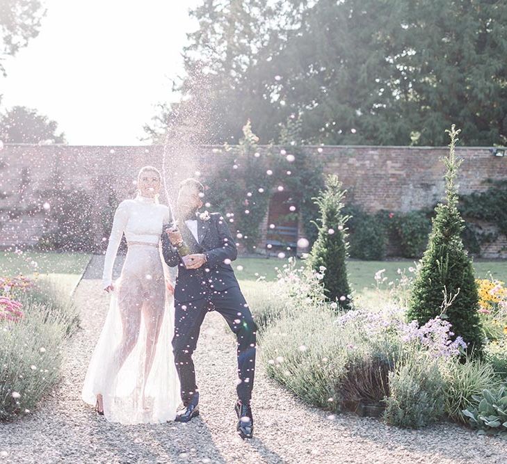 Bride and groom spraying champagne in the gardens at Garthmyl Hall wedding venue 