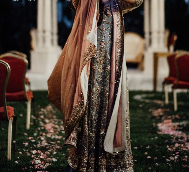 Bride wears beautiful and brightly coloured saree as she holds hand in the air showing her henna