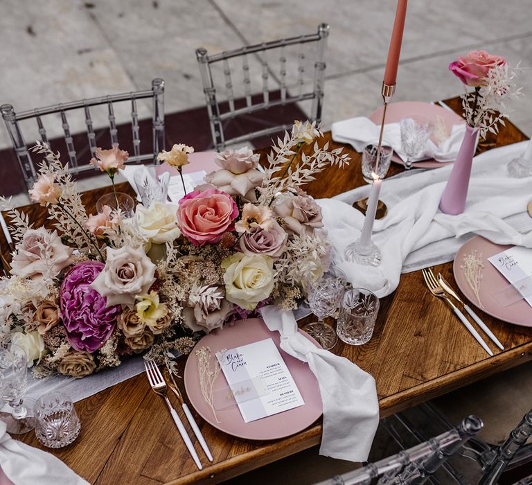 Elegant tablescape decor with pink tableware, cut glass, taper candles and pink floral arrangements 