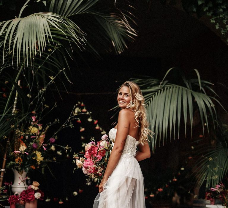 Bride at finca wedding in Spain wearing sheer split skirt wedding dress, holding a pink bouquet