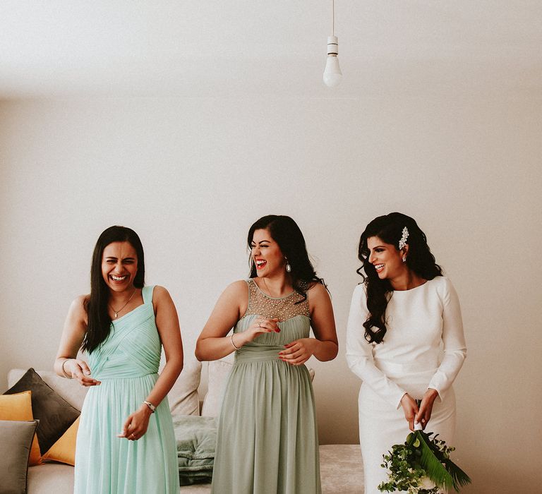 Bride and bridesmaids in different dresses on the wedding morning laughing together 