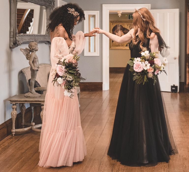 Two brides seeing each other for the first time in their blush pink and black coloured wedding dresses for an autism marriage