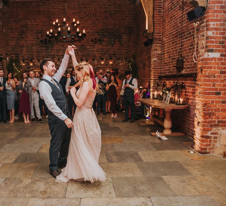 Bride and groom first dance at Hazel Gap Barn wedding venue with bride in a blush wedding dress and burgundy bow in her hair