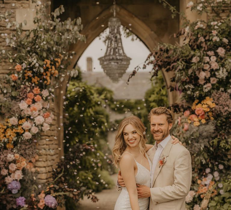 Confetti moment at the Castle Arch at Euridge Manor with chandelier. The bride wears Made With Love dresses and the groom a beige suit 